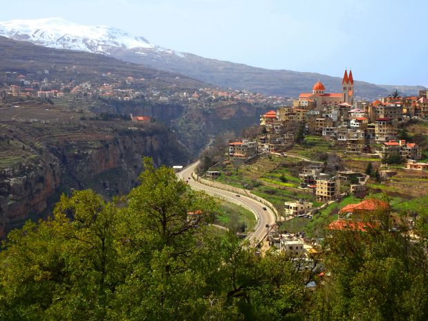 Hill town of Bsharri and Qadisha Valley (Kadisha Gorge Wadi Kadisha Ouadi Qadisha) Bcharreh, Liban-Nord, Lebanon. City on hill with Saint Saba Cathedral and valley with snow peak of Mount Lebanon.